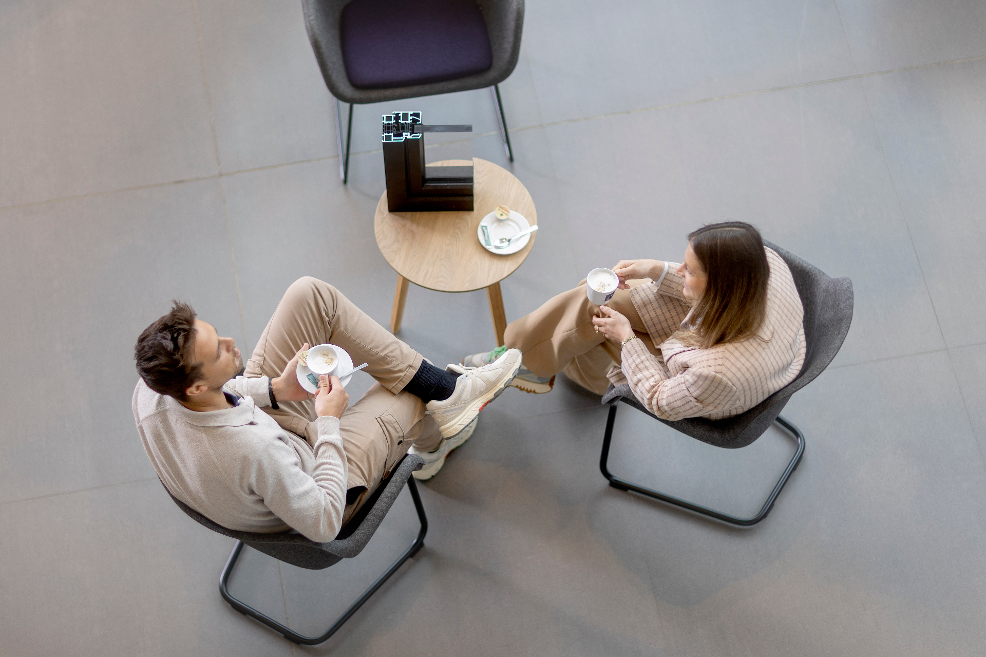 Twee Reynaers Aluminium-collega's in gesprek bij een koffie naast een aluminium hoekprofiel